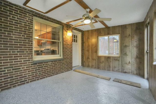 interior space with ceiling fan and brick wall