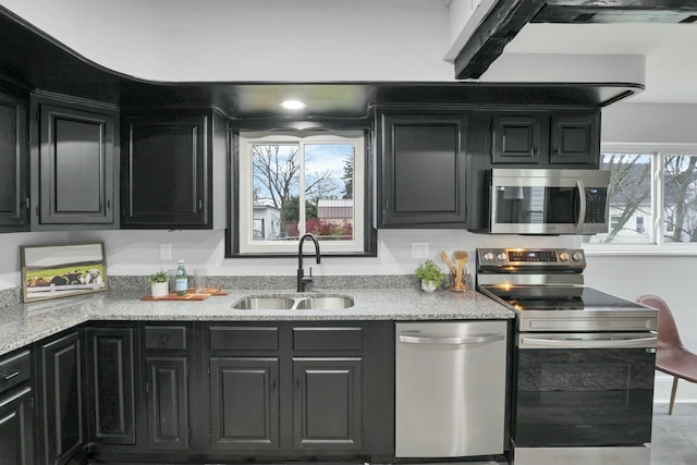 kitchen featuring stainless steel appliances, light stone counters, and sink