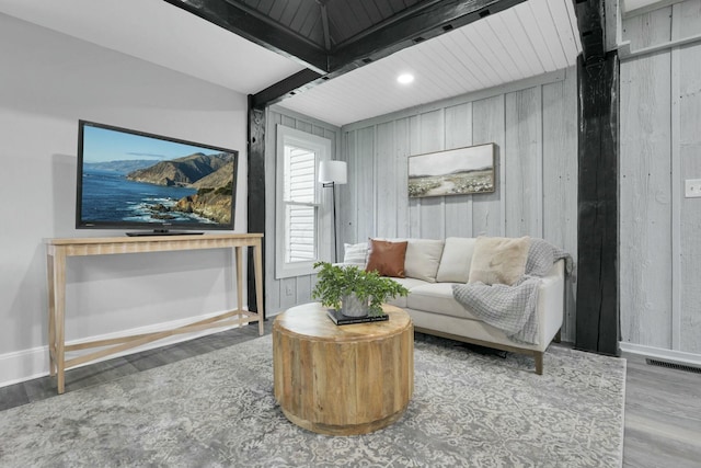 living room featuring wooden walls, beamed ceiling, and hardwood / wood-style flooring