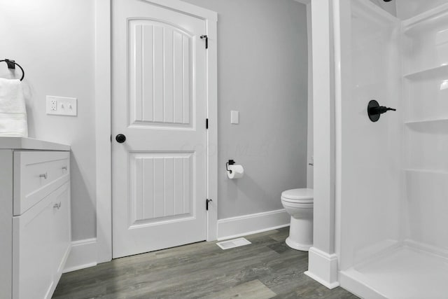 bathroom with hardwood / wood-style floors, vanity, toilet, and walk in shower