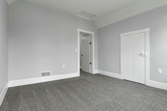 unfurnished bedroom with dark colored carpet and lofted ceiling