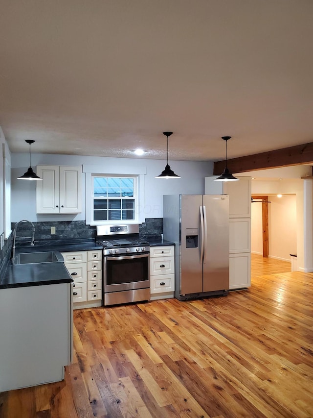 kitchen featuring white cabinets, decorative light fixtures, light wood-type flooring, and appliances with stainless steel finishes