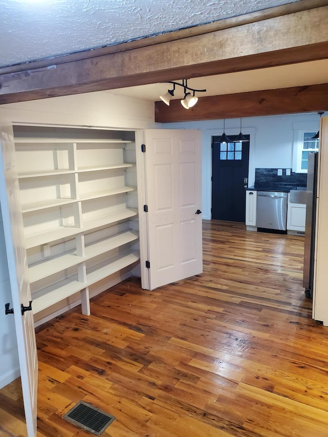 interior space with beamed ceiling, a textured ceiling, and hardwood / wood-style flooring