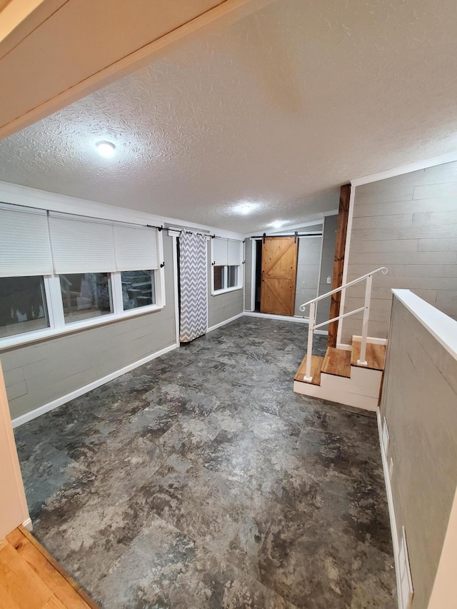 interior space with a barn door and a textured ceiling