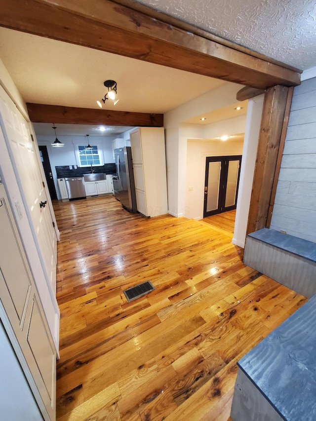 corridor featuring a textured ceiling, light hardwood / wood-style flooring, and sink