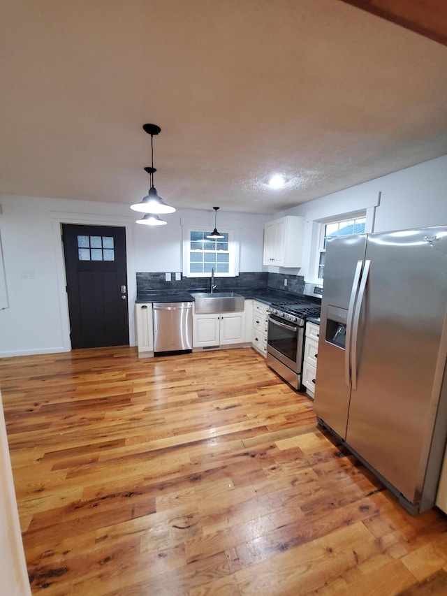 kitchen featuring sink, stainless steel appliances, light hardwood / wood-style flooring, decorative light fixtures, and white cabinets