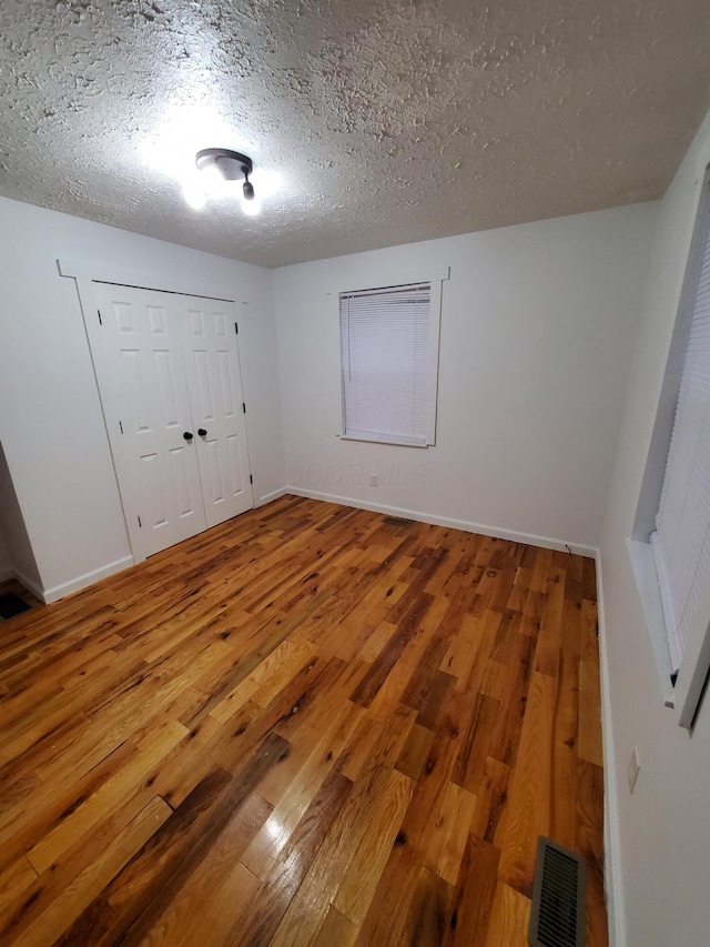 interior space with a textured ceiling and hardwood / wood-style flooring