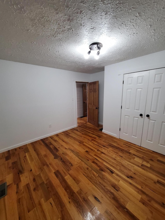 unfurnished bedroom featuring hardwood / wood-style floors, a textured ceiling, and a closet