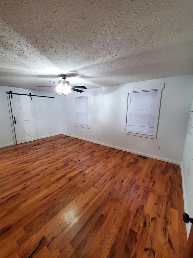 spare room with wood-type flooring, a barn door, and a textured ceiling