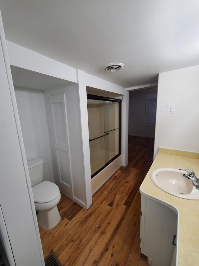 bathroom with wood-type flooring, vanity, toilet, and an enclosed shower