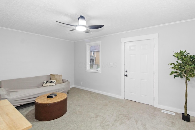 living room with ceiling fan, crown molding, light colored carpet, and a textured ceiling