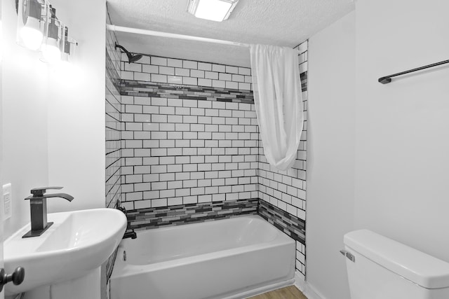 full bathroom with sink, toilet, shower / bath combo with shower curtain, a textured ceiling, and wood-type flooring