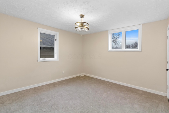 carpeted spare room featuring a textured ceiling