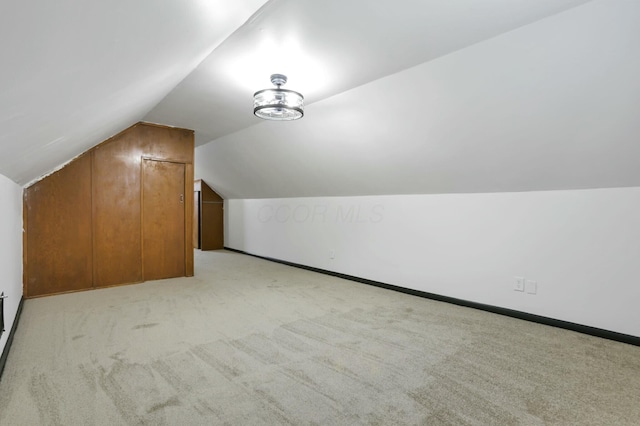 additional living space featuring lofted ceiling and light carpet