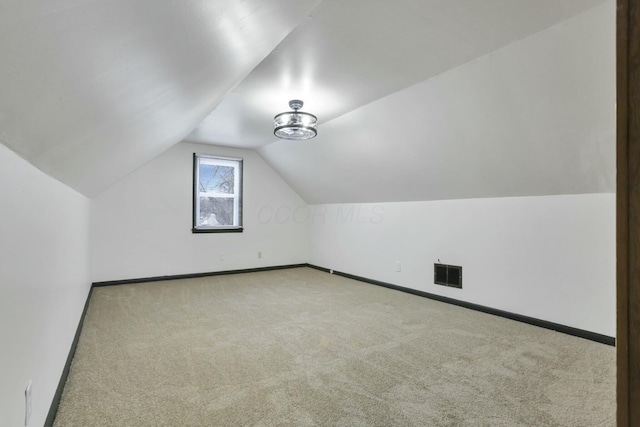 bonus room with light carpet and vaulted ceiling