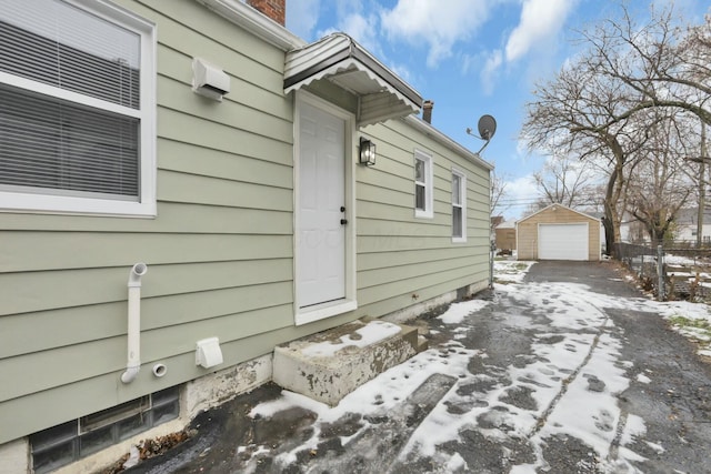 snow covered property featuring an outbuilding and a garage