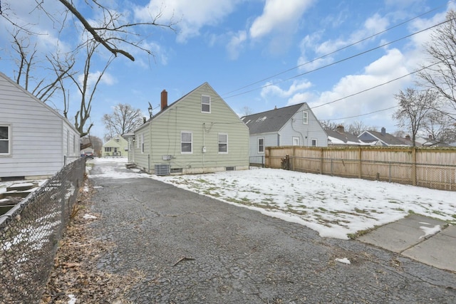 snow covered back of property featuring central AC