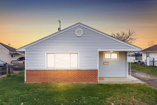 back house at dusk featuring a lawn