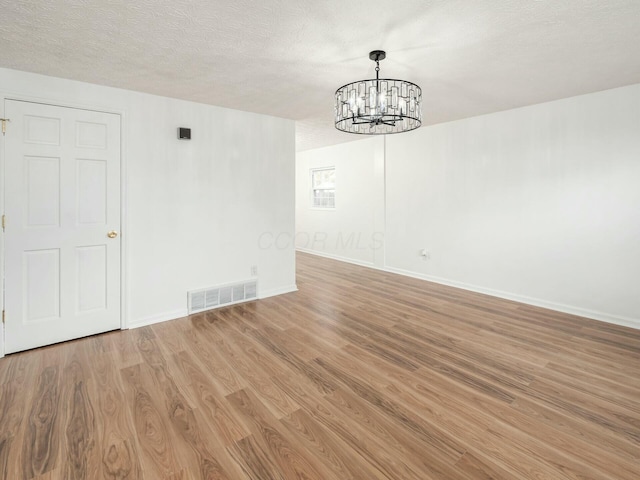 interior space featuring light wood-type flooring, a textured ceiling, and a chandelier