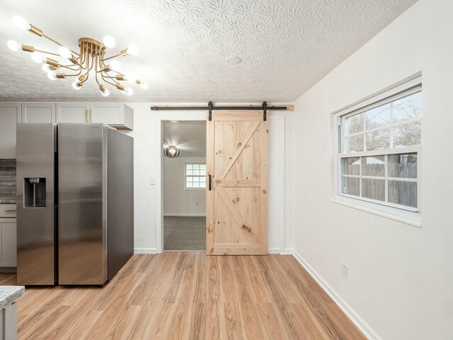 5006 Old Tree Ave, Columbus, OH 43228 - kitchen featuring stainless steel fridge, a textured ceiling, light wood-type flooring, a barn door, and a chandelier