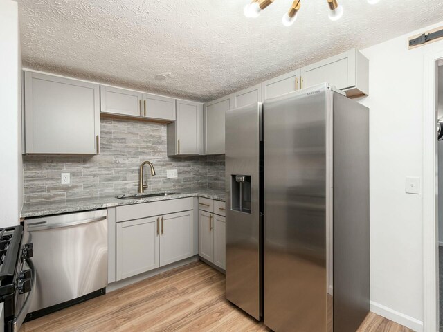 5006 Old Tree Ave, Columbus, OH 43228 - kitchen featuring stainless steel appliances, gray cabinetry, light wood-style floors, light stone countertops, and backsplash