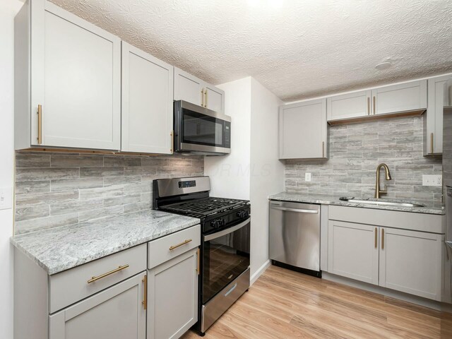 5006 Old Tree Ave, Columbus, OH 43228 - kitchen featuring appliances with stainless steel finishes, gray cabinetry, light stone counters, tasteful backsplash, and a textured ceiling