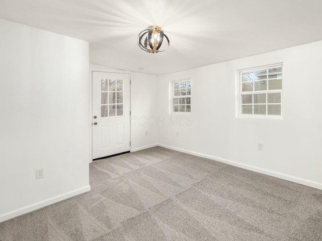 unfurnished room featuring light carpet and an inviting chandelier