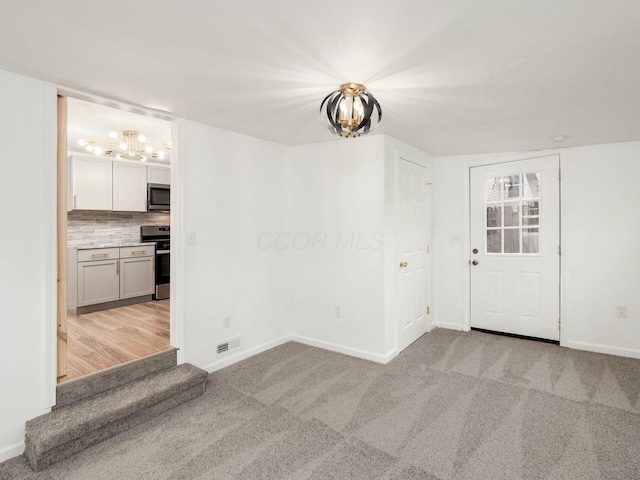 unfurnished room featuring light carpet and an inviting chandelier