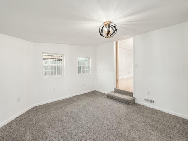 carpeted spare room featuring a chandelier