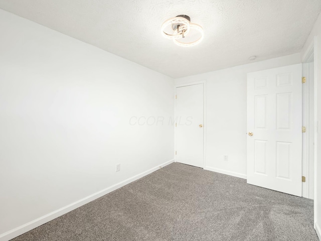 empty room with dark carpet and a textured ceiling