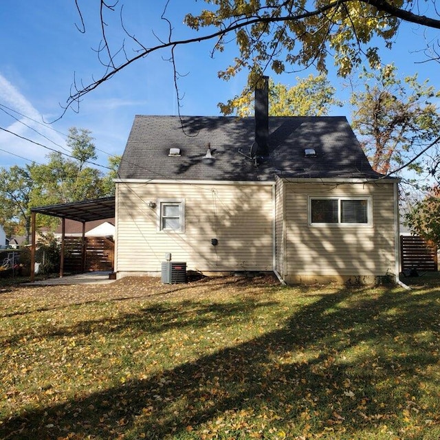 rear view of house featuring central air condition unit, a yard, and a carport