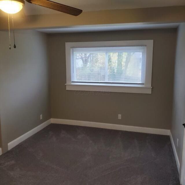 empty room featuring dark colored carpet and ceiling fan