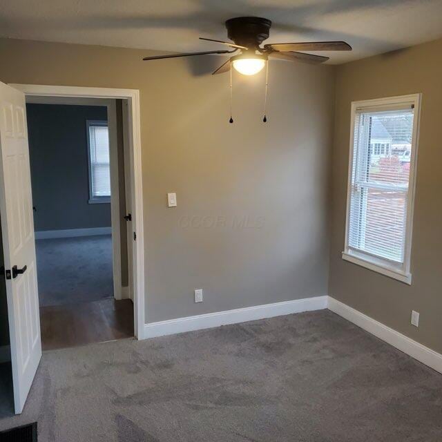 carpeted spare room featuring ceiling fan and a healthy amount of sunlight