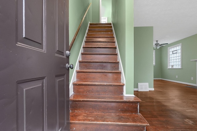 stairs featuring hardwood / wood-style flooring and ceiling fan