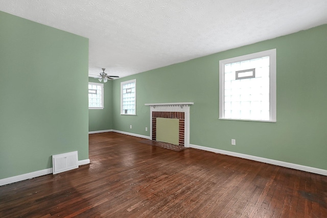 unfurnished living room featuring a fireplace, ceiling fan, dark hardwood / wood-style flooring, and a textured ceiling