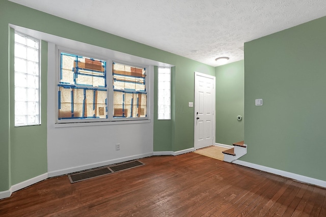 foyer entrance with wood-type flooring, a textured ceiling, and a healthy amount of sunlight