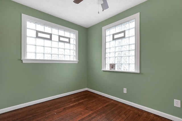 empty room featuring ceiling fan, dark wood-type flooring, and a textured ceiling