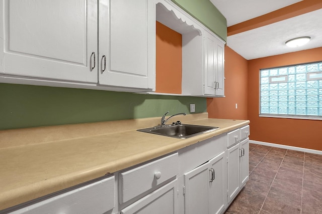 kitchen with sink, white cabinets, and dark tile patterned flooring