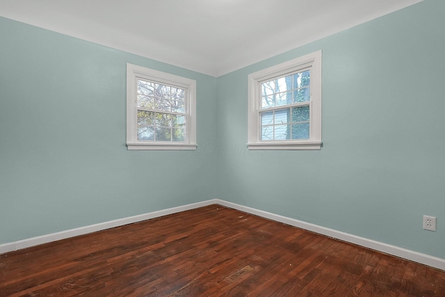 empty room with a healthy amount of sunlight and dark hardwood / wood-style floors