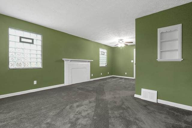 interior space with plenty of natural light, dark carpet, a textured ceiling, and ceiling fan