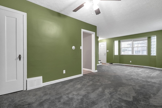 unfurnished room featuring a textured ceiling, dark carpet, and ceiling fan