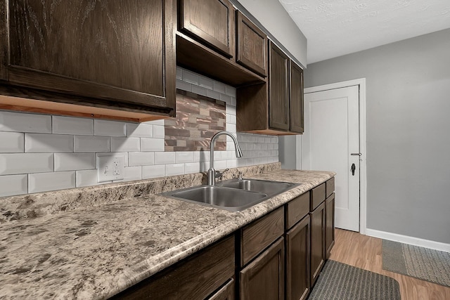 kitchen with decorative backsplash, sink, light hardwood / wood-style floors, and dark brown cabinets