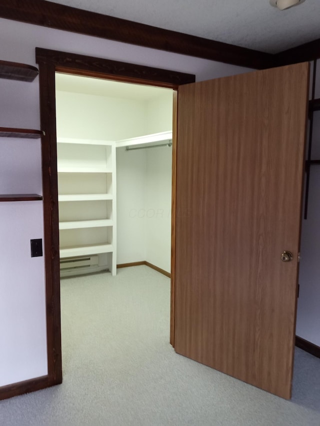 walk in closet with beamed ceiling and light colored carpet