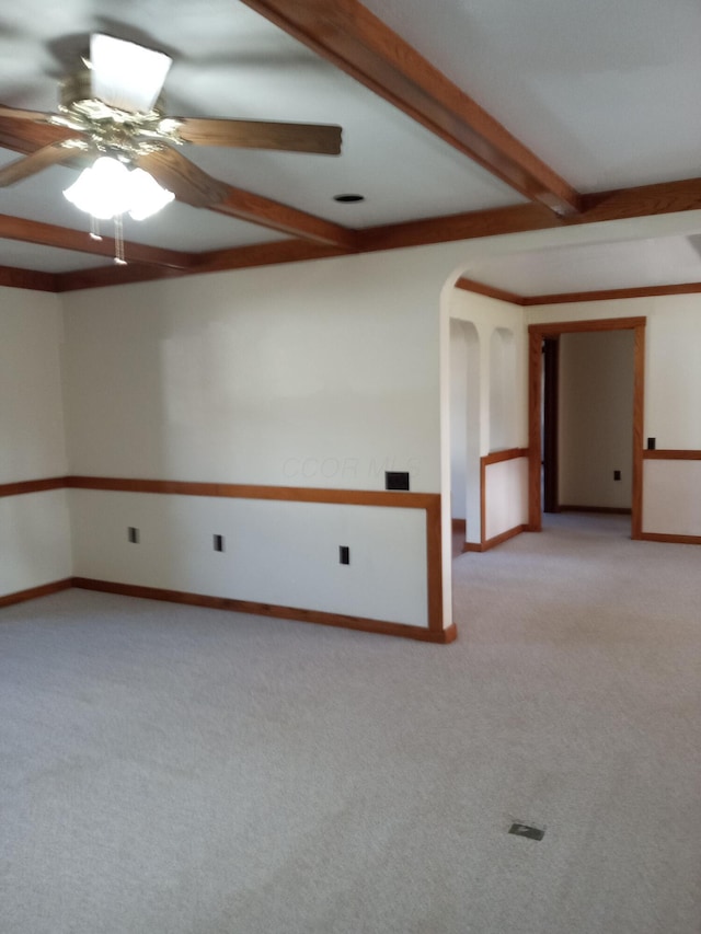 unfurnished room featuring beamed ceiling, ceiling fan, and light colored carpet