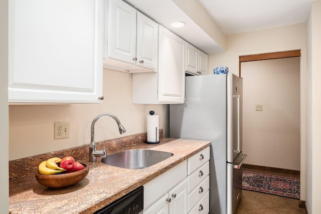 kitchen with white cabinetry, sink, stainless steel fridge, dark tile patterned flooring, and light stone countertops