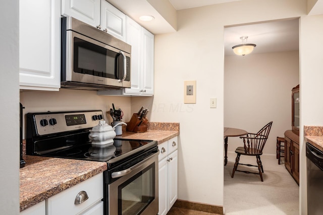 kitchen with dark stone counters, white cabinets, and appliances with stainless steel finishes