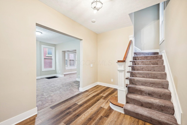 stairs featuring hardwood / wood-style floors and a textured ceiling