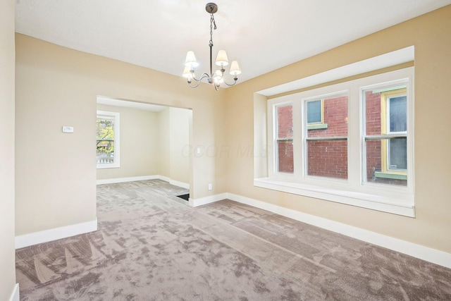 empty room with carpet floors and an inviting chandelier