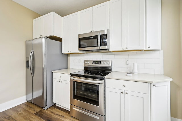 kitchen with white cabinets, dark hardwood / wood-style floors, decorative backsplash, and stainless steel appliances