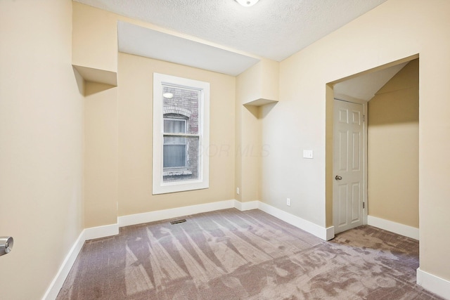 carpeted empty room featuring a textured ceiling